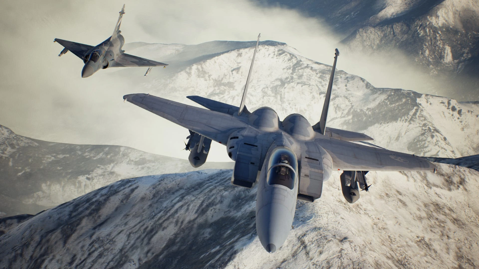 Un F-15 gris vuela de frente sobre montañas nevadas, con un caza de alas en delta detrás a la izquierda