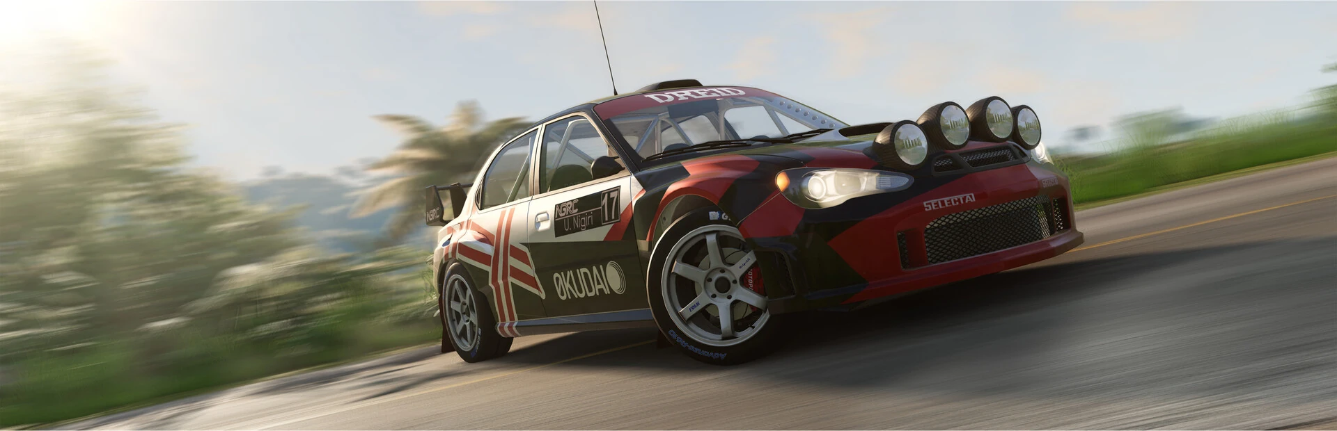 Un coche de rally negro y rojo con cuatro faros en el techo toma una curva de asfalto a toda velocidad entre palmeras