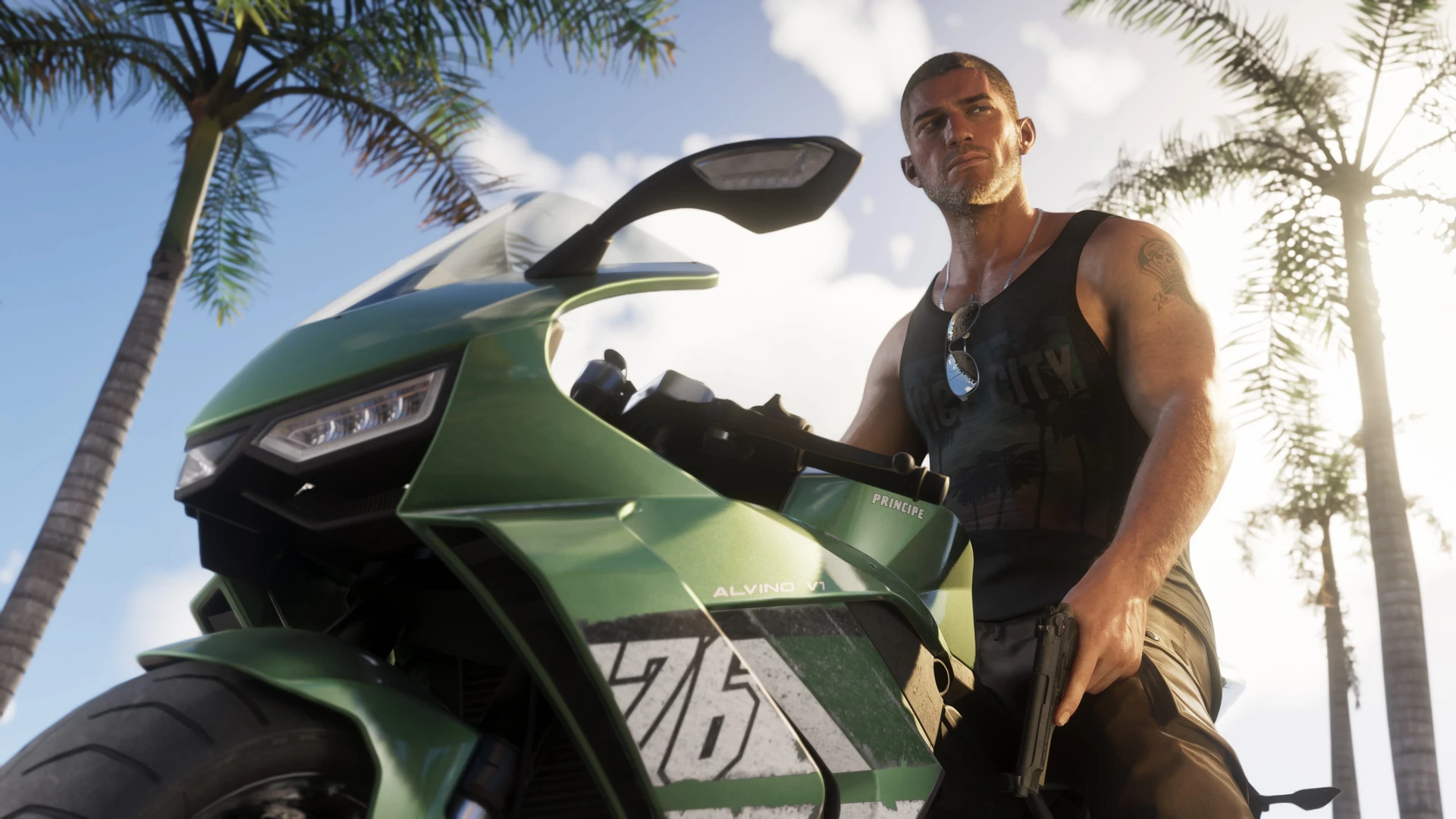 Jason Duval, con camiseta de tirantes y gafas de sol colgadas al cuello, de pie junto a una motocicleta deportiva verde entre palmeras