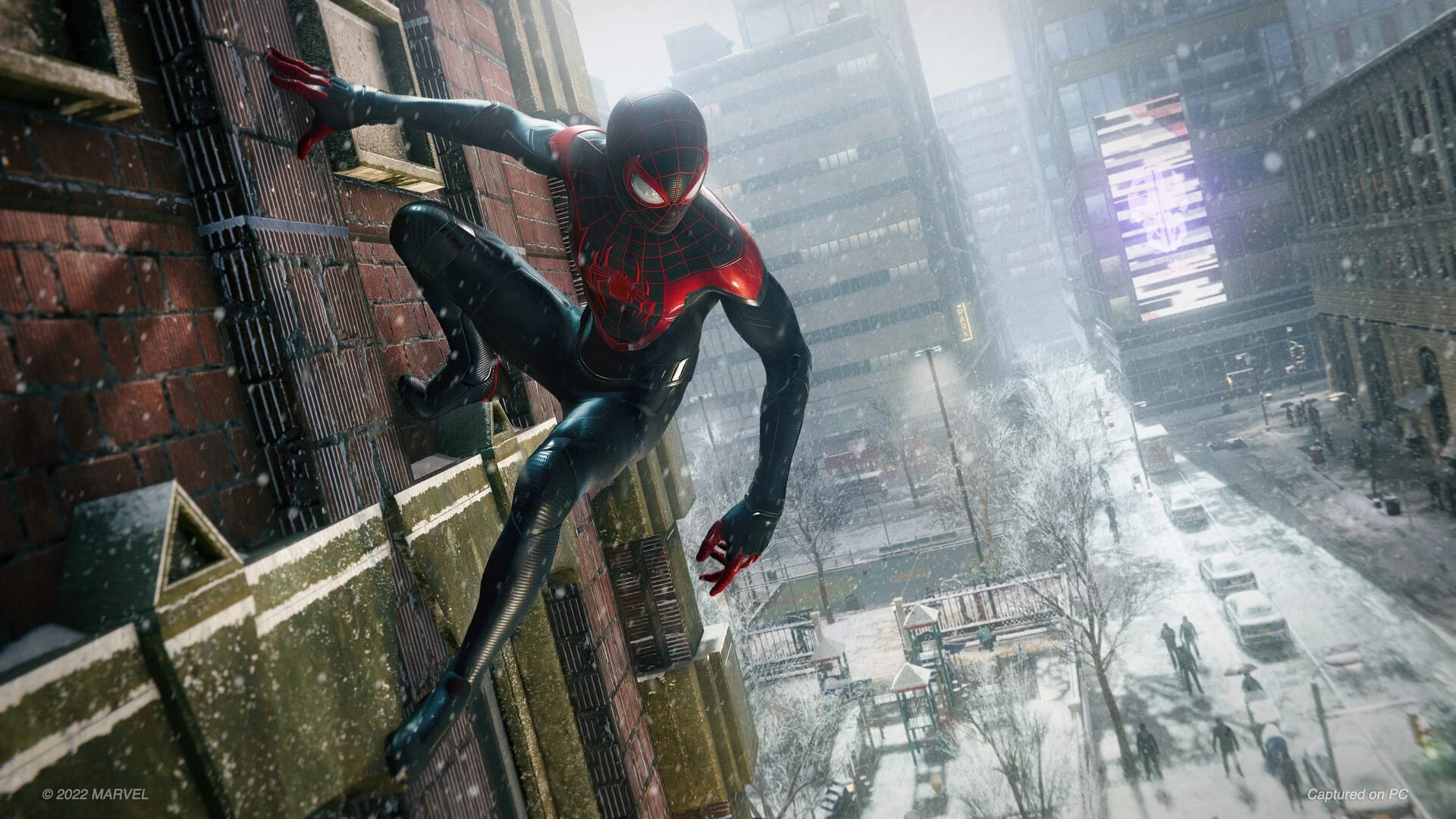 Miles Morales agarrado a la pared de un edificio de ladrillo sobre una calle cubierta de nieve