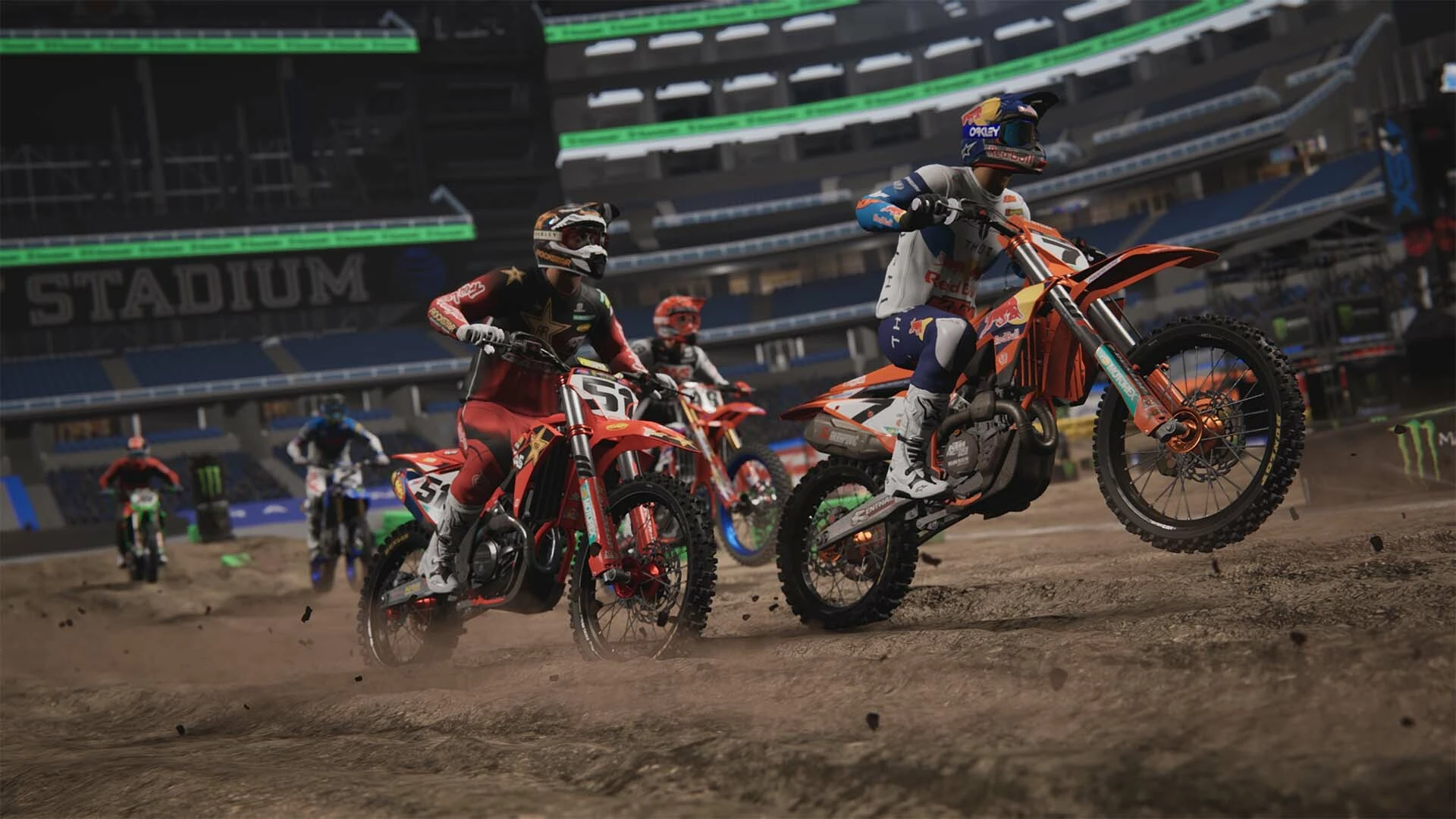 Varios pilotos salen de una curva de tierra dentro de un estadio cubierto, con una KTM naranja en cabeza