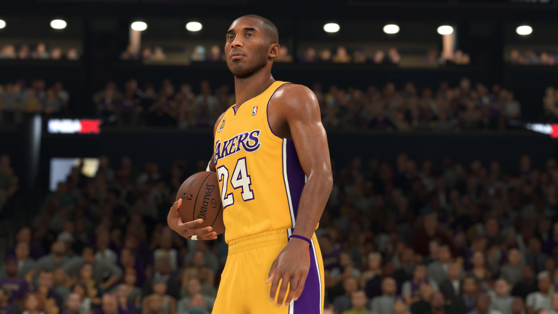 Kobe Bryant, con la camiseta amarilla número 24 de los Lakers, sujeta el balón en un pabellón lleno de público