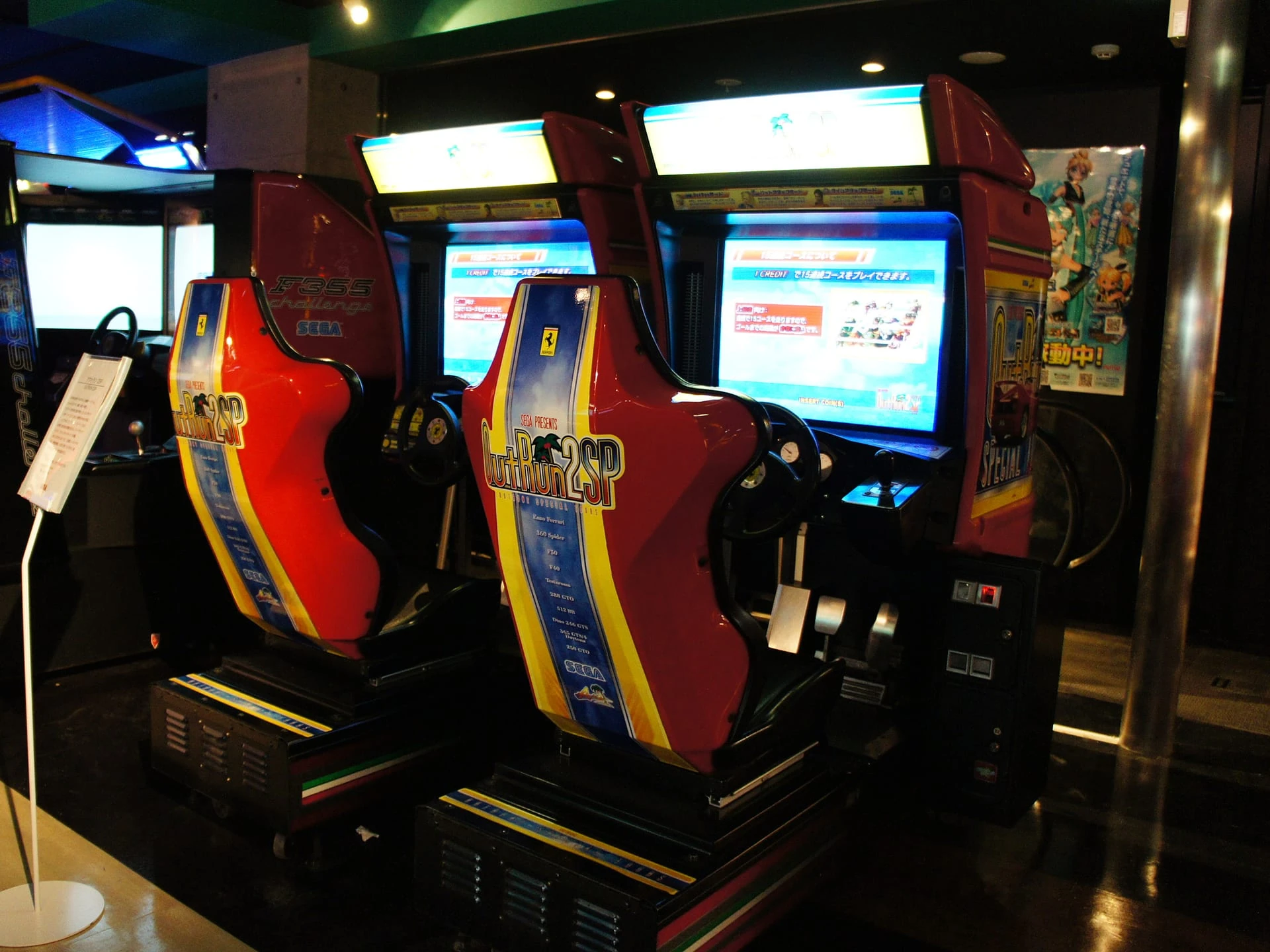 Dos muebles de OutRun 2 SP en un salón recreativo, con asientos de carreras rojos, azules y amarillos delante de las pantallas