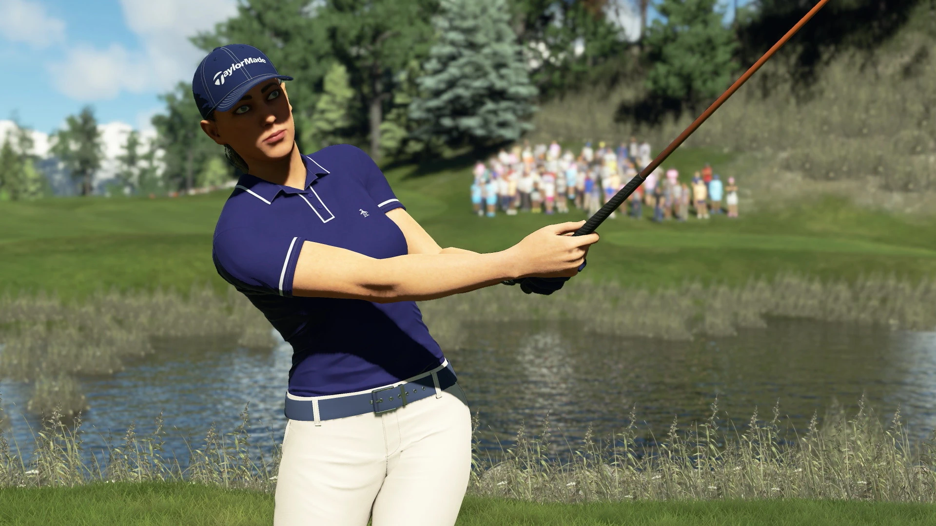 Un golfista con gorra y polo azul sigue con la mirada su golpe junto a un estanque, con público al fondo
