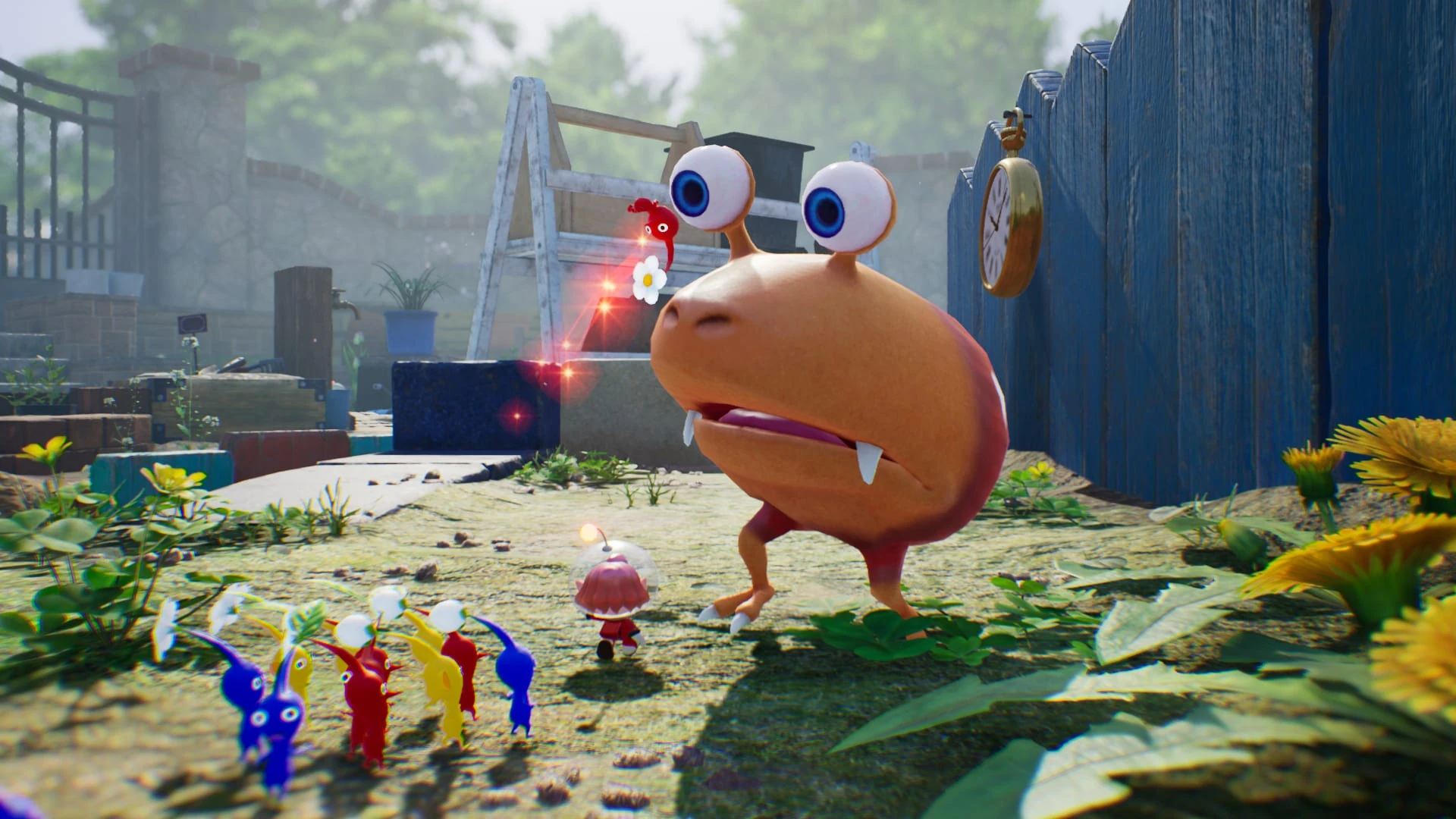 Un grupo de Pikmin rojos, azules, amarillos y blancos se enfrenta a un bicho naranja enorme de ojos saltones en un jardín, junto a una valla azul