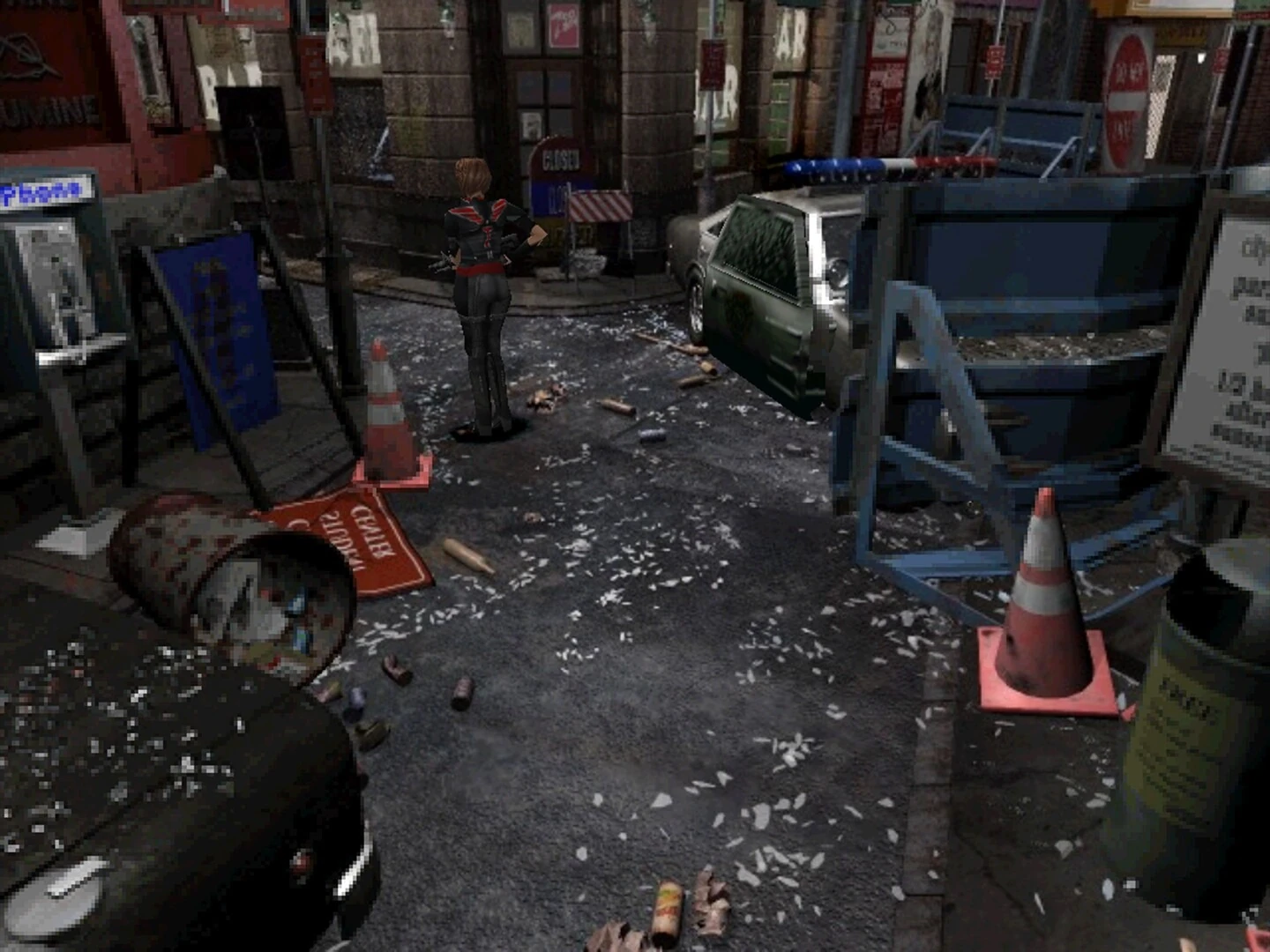 Una calle de Raccoon City sembrada de escombros, conos y un coche de policía, con un zombi al fondo