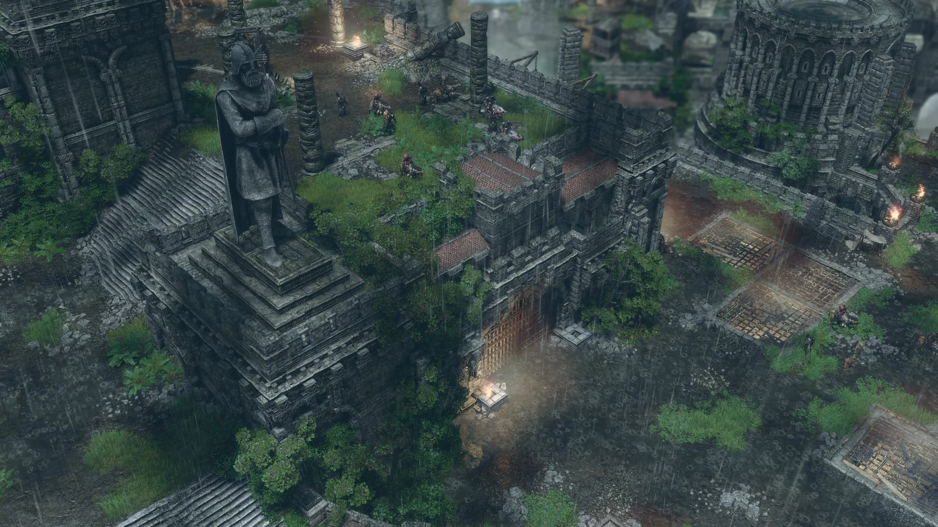 Vista aérea de una ciudad en ruinas cubierta de hierba, con una gran estatua de piedra sobre un pedestal escalonado