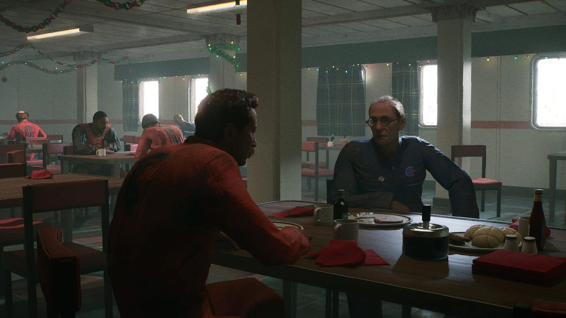 Dos trabajadores conversan en una mesa del comedor de la plataforma, adornado con guirnaldas navideñas