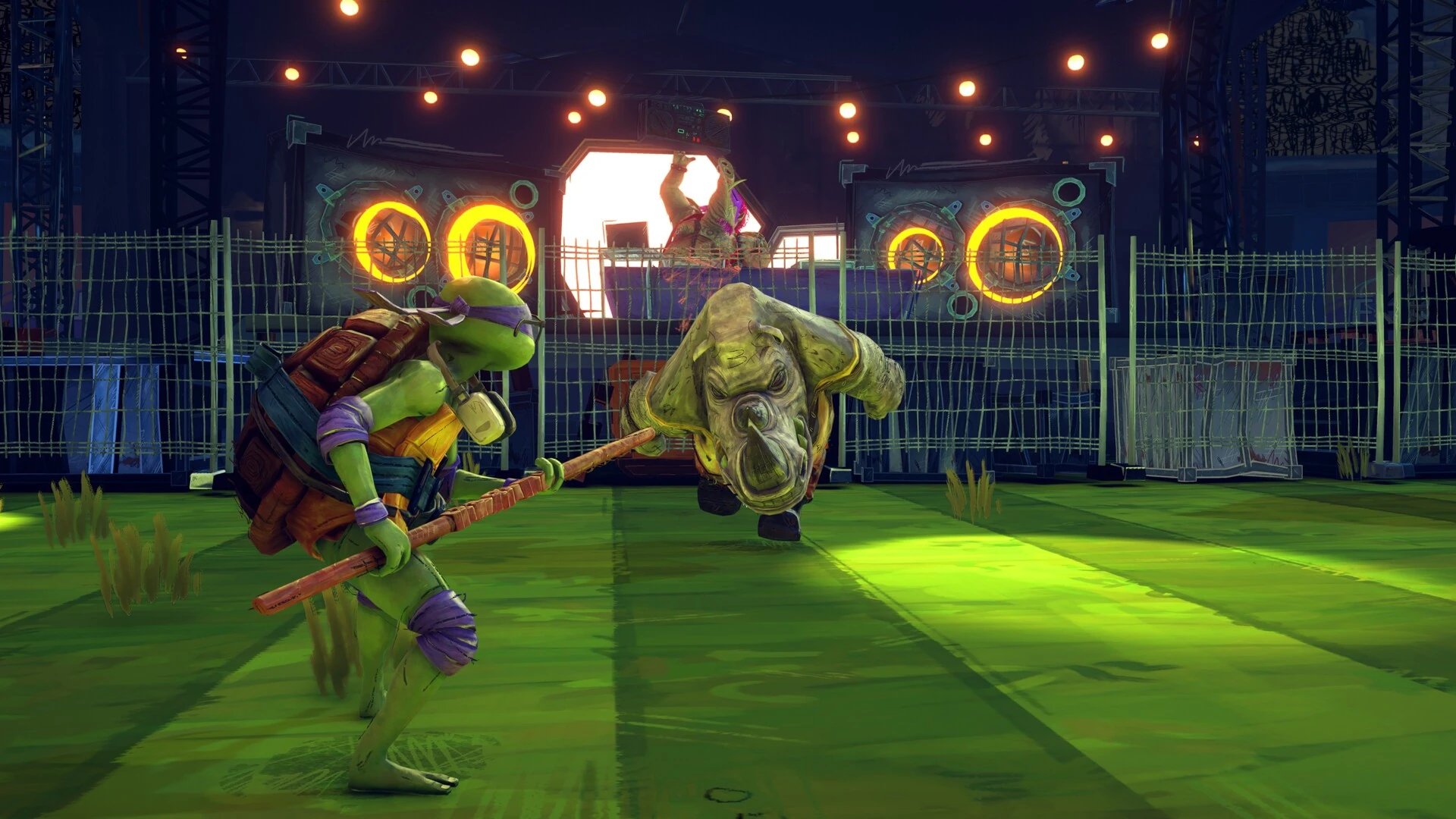 Donatello, con su bastón, frente a Rocksteady sobre un campo de césped iluminado por focos y altavoces