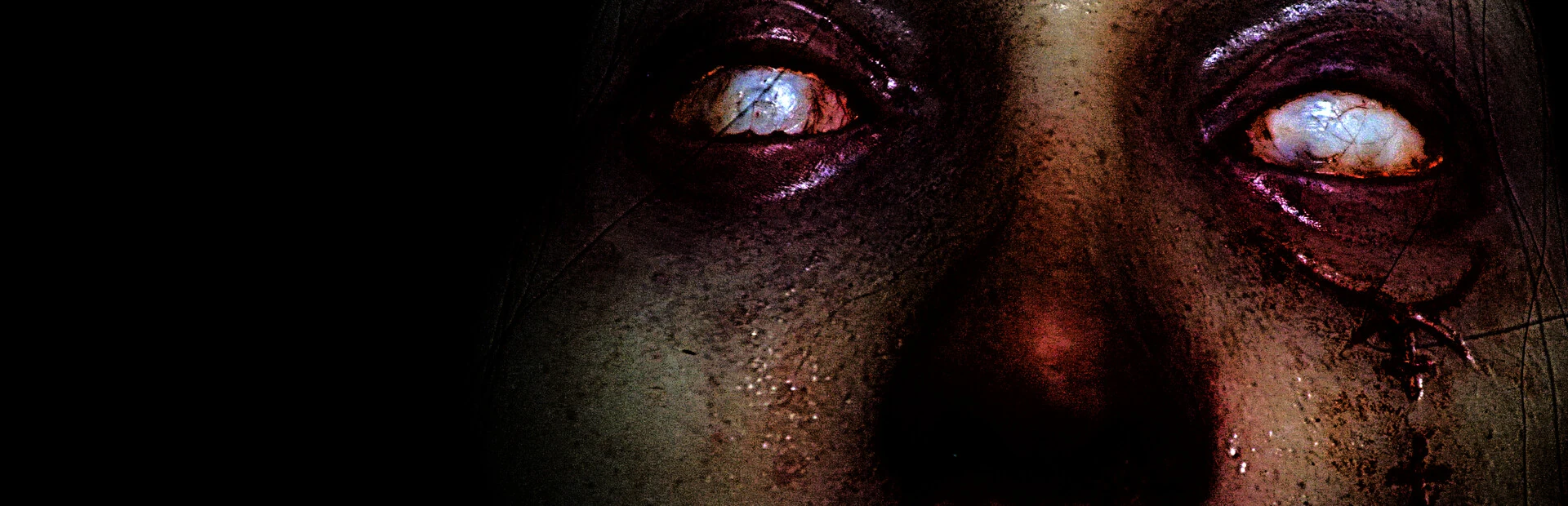 Primer plano de un rostro maquillado como un monstruo, con los ojos blancos y lechosos y la piel sucia y agrietada