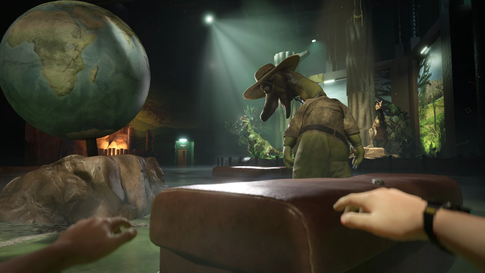 Un globo terráqueo gigante y una mascota de dinosaurio con sombrero, de espaldas, en una sala de exposición a oscuras