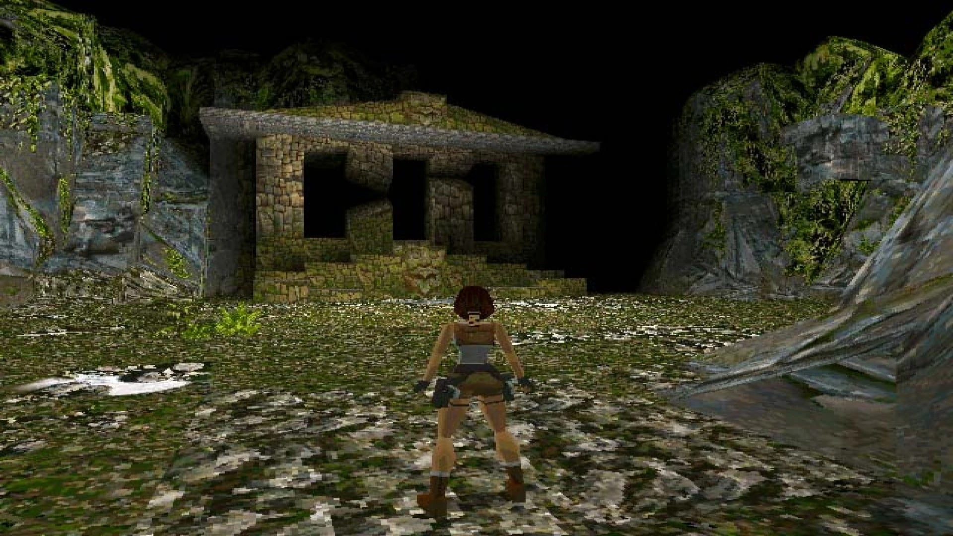 Lara Croft, de espaldas, ante un templo de piedra cubierto de musgo en un valle cerrado por paredes de roca