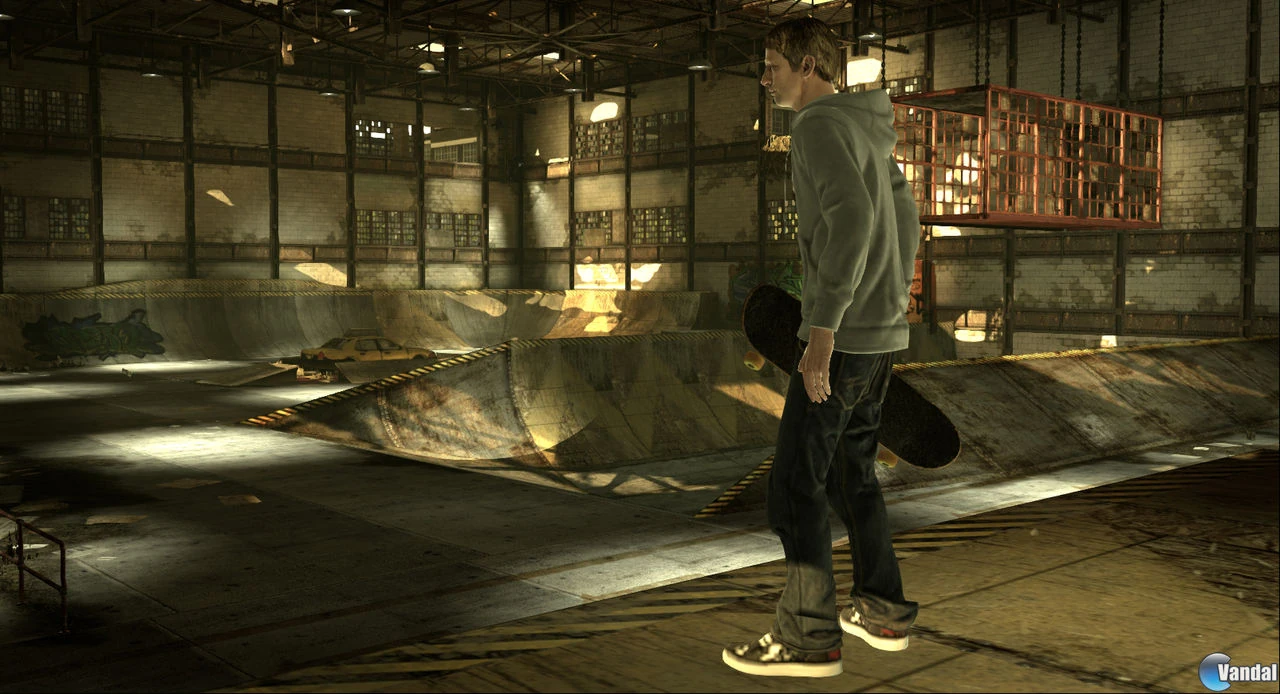 Tony Hawk, con sudadera y la tabla bajo el brazo, en un almacén en penumbra lleno de rampas y un taxi amarillo al fondo
