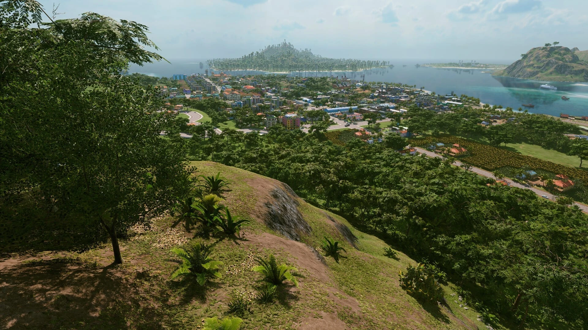 Una ciudad tropical entre árboles junto a una bahía, vista desde lo alto de una colina, con islas al fondo