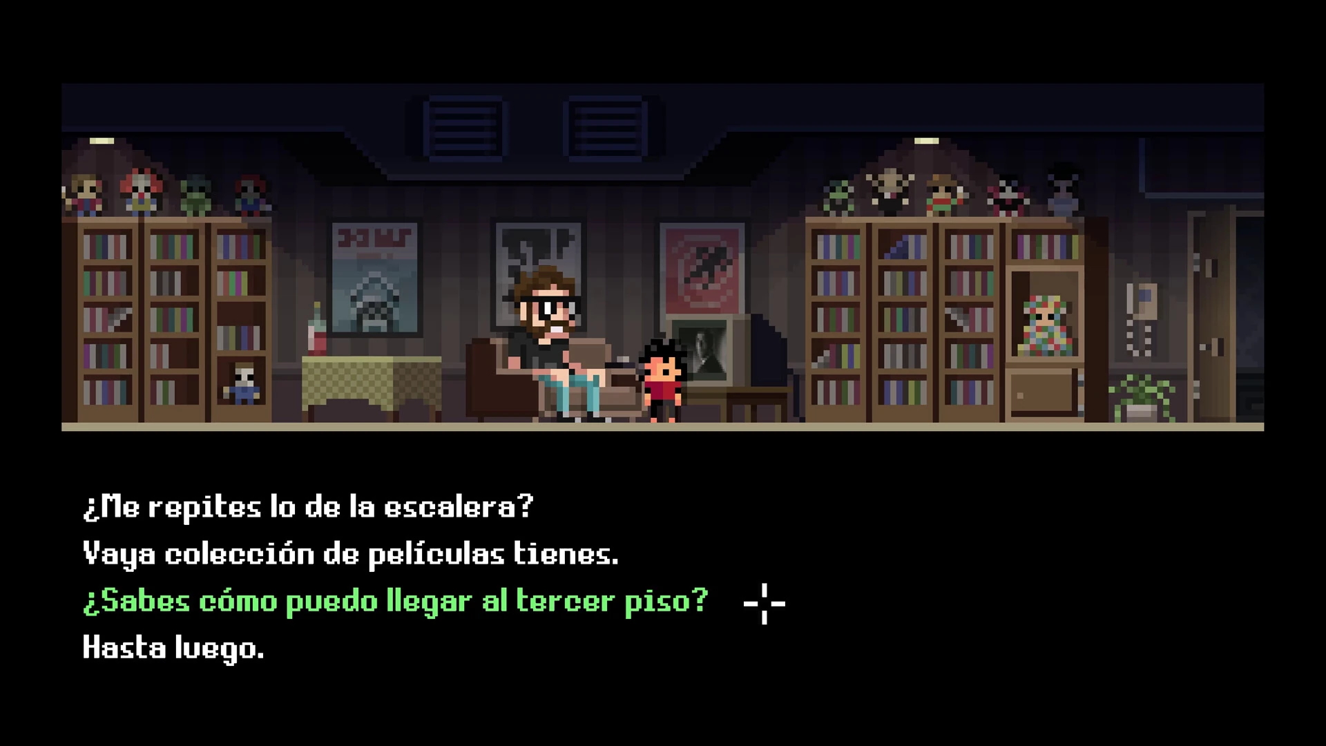 Un salón con estanterías de películas y muñecos de terror; un hombre con barba y gafas, sentado en un sofá, y el protagonista de pie a su lado