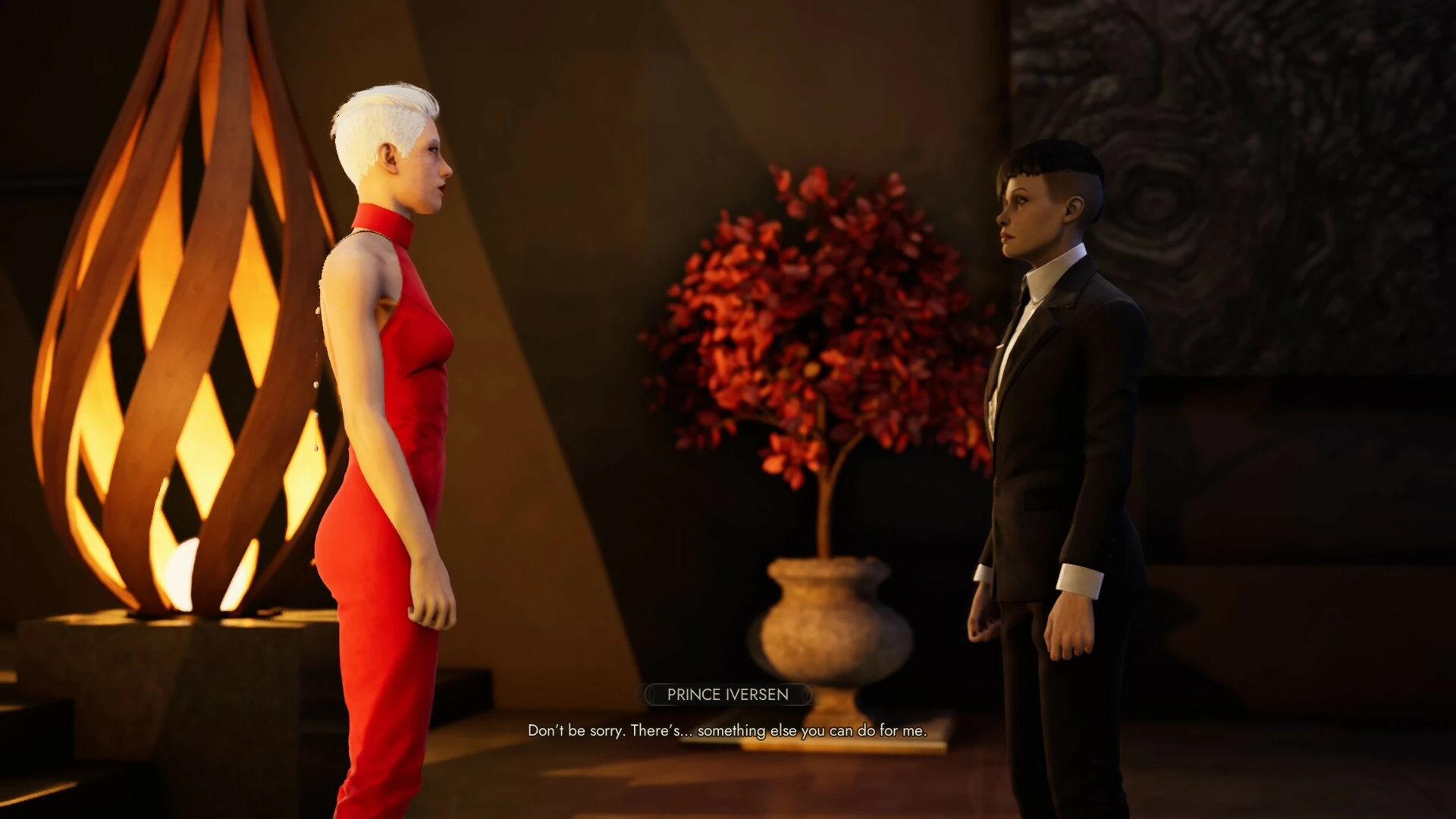 Una vampira de pelo blanco y vestido rojo frente a la príncipe Iversen, de traje negro, en un salón con una lámpara de madera encendida