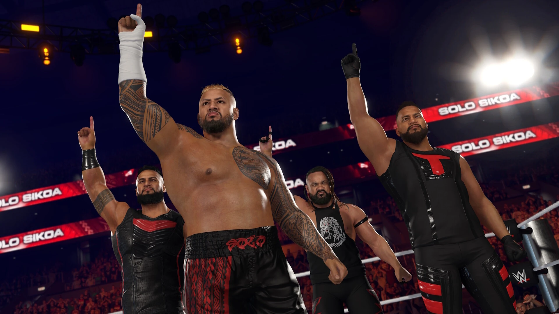 Cuatro luchadores de negro y rojo señalan al techo desde el ring, bajo rótulos con el nombre de Solo Sikoa