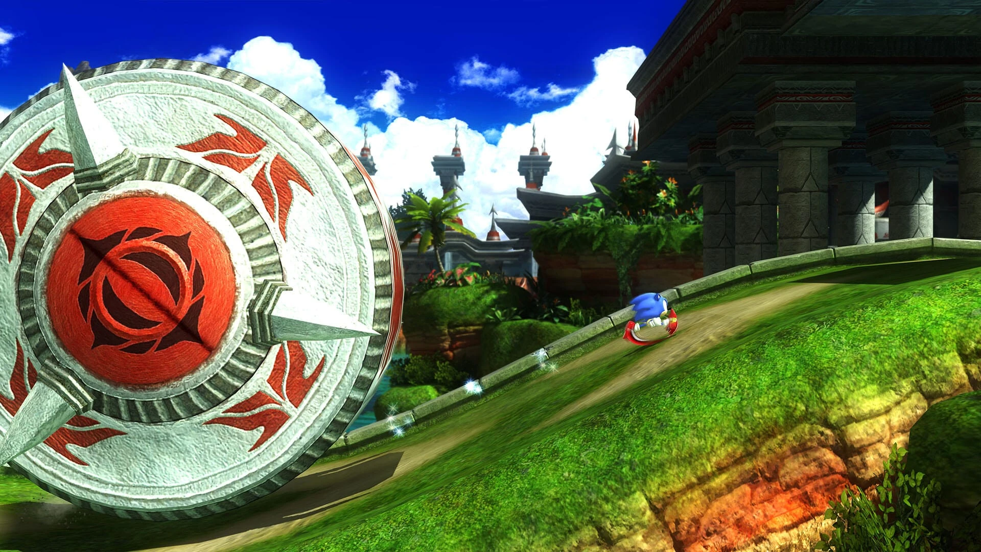 Sonic rueda hecho una bola por una loma verde de Green Hill, junto a un enorme tótem de piedra con un adorno rojo, bajo un cielo azul con nubes