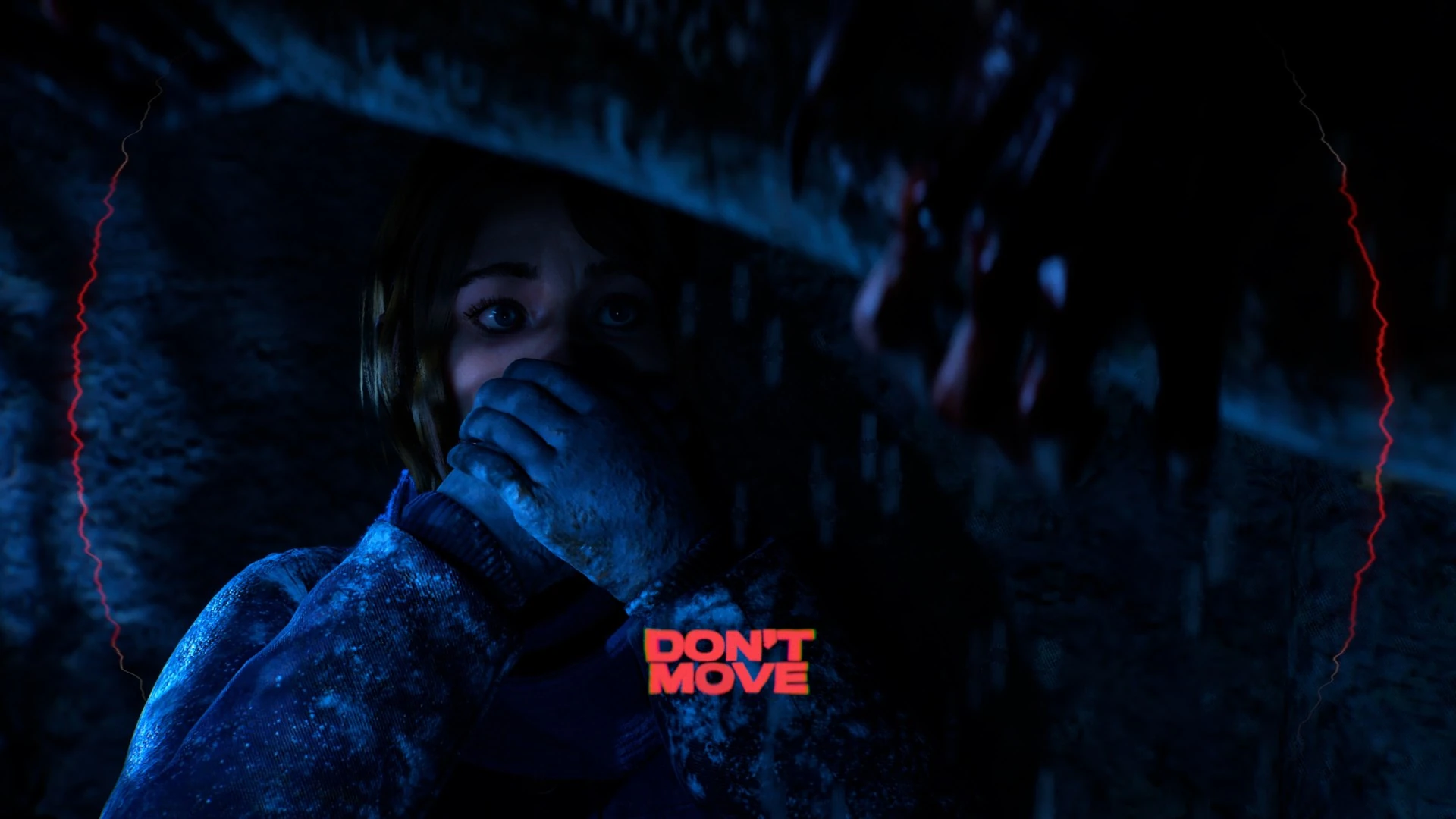 Una chica escondida bajo una estructura, tapándose la boca con la mano, iluminada de azul; en rojo, el rótulo «Don't move»