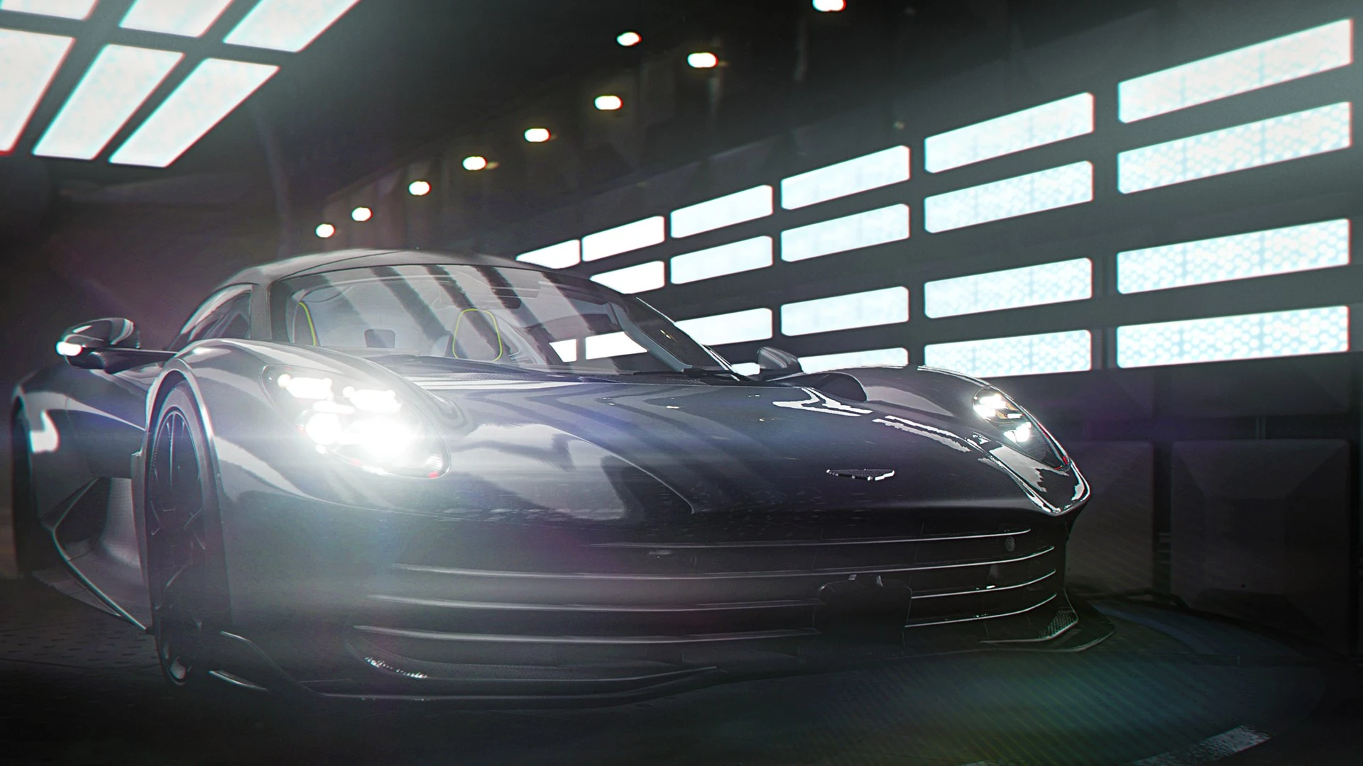 El Aston Martin Valhalla plateado, con los faros encendidos, en un hangar con paneles de luz blanca en la pared