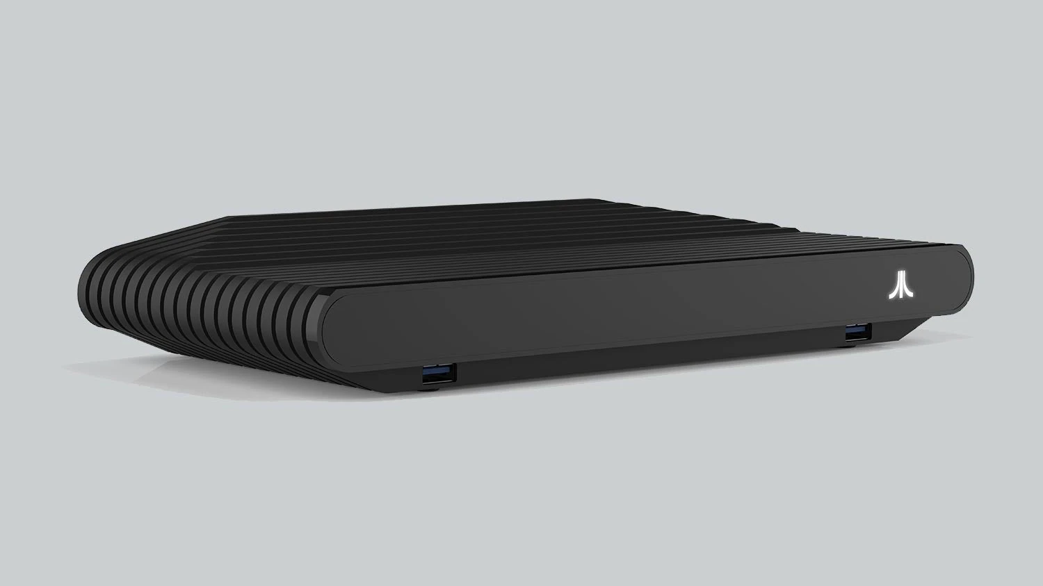 La Atari VCS en negro, una caja baja y alargada con estrías en la tapa y el logotipo de Atari en la esquina, sobre fondo gris
